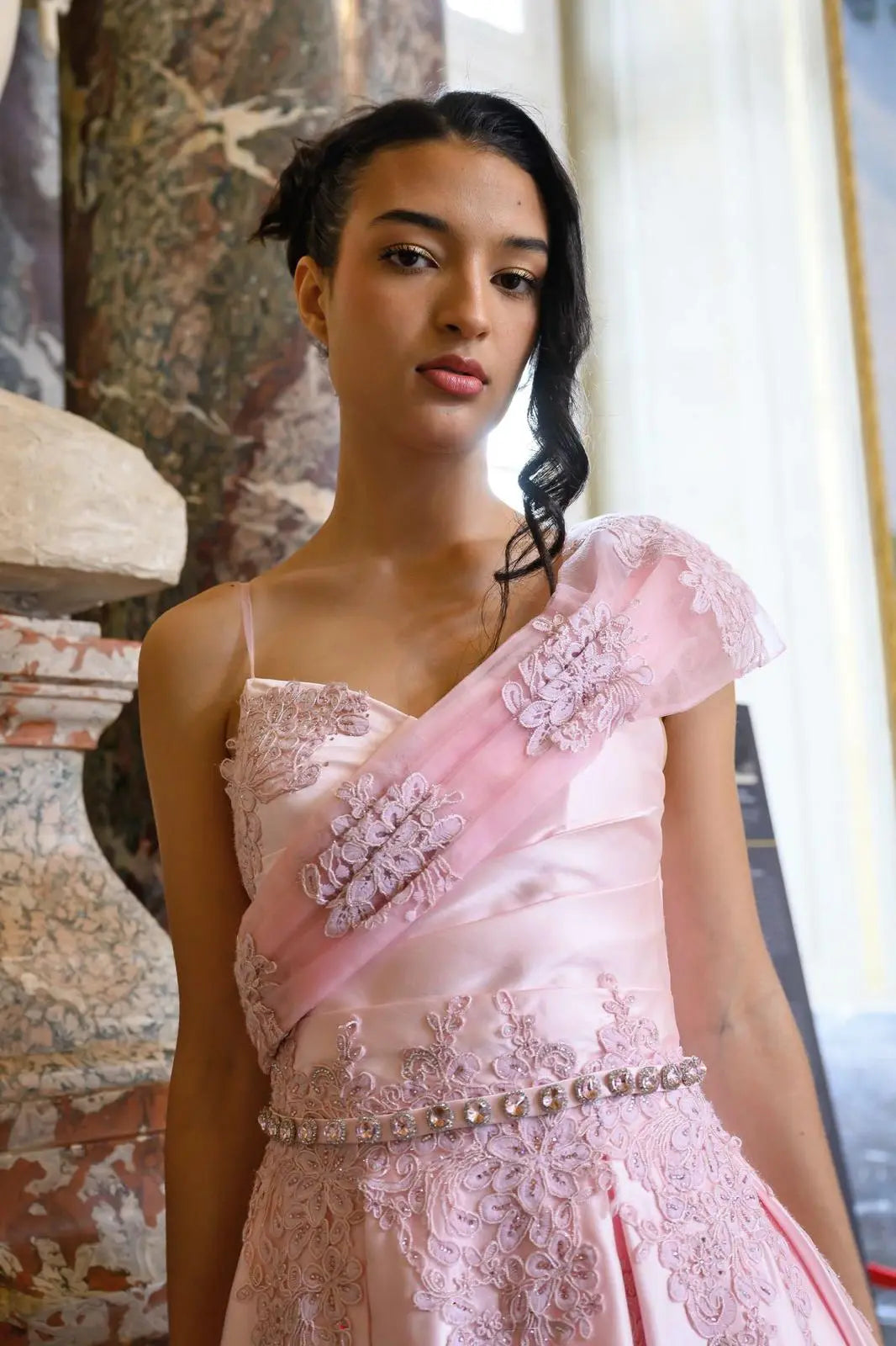 Robe travaillée avec Du satin duchesse, des appliques de dentelle ornées de strass, la large bretelle asymétrique la rend originale et moderne 